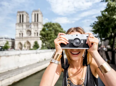 young woman tourist photographing with camera standing front famous notre dame cathedral paris